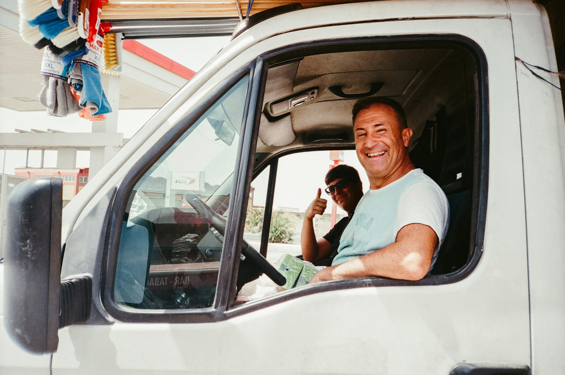 Smiling driver in a white van, his colleague giving a thumbs up